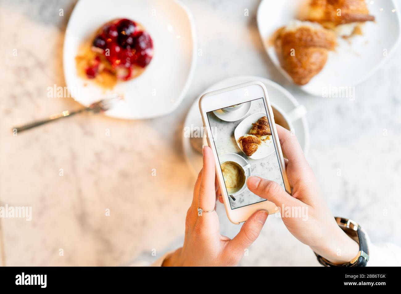 Woman taking photos of her breakfast on her mobile phone Stock Photo