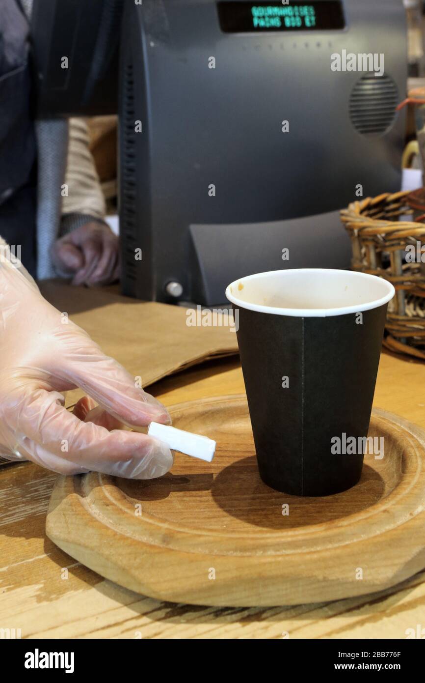 Boulangère vendant un café dans un gobelet en carton avec des gants de protection. Coronavirus. Covid-19.Saint-Gervais-les-Bains. Haute-Savoie. France Stock Photo