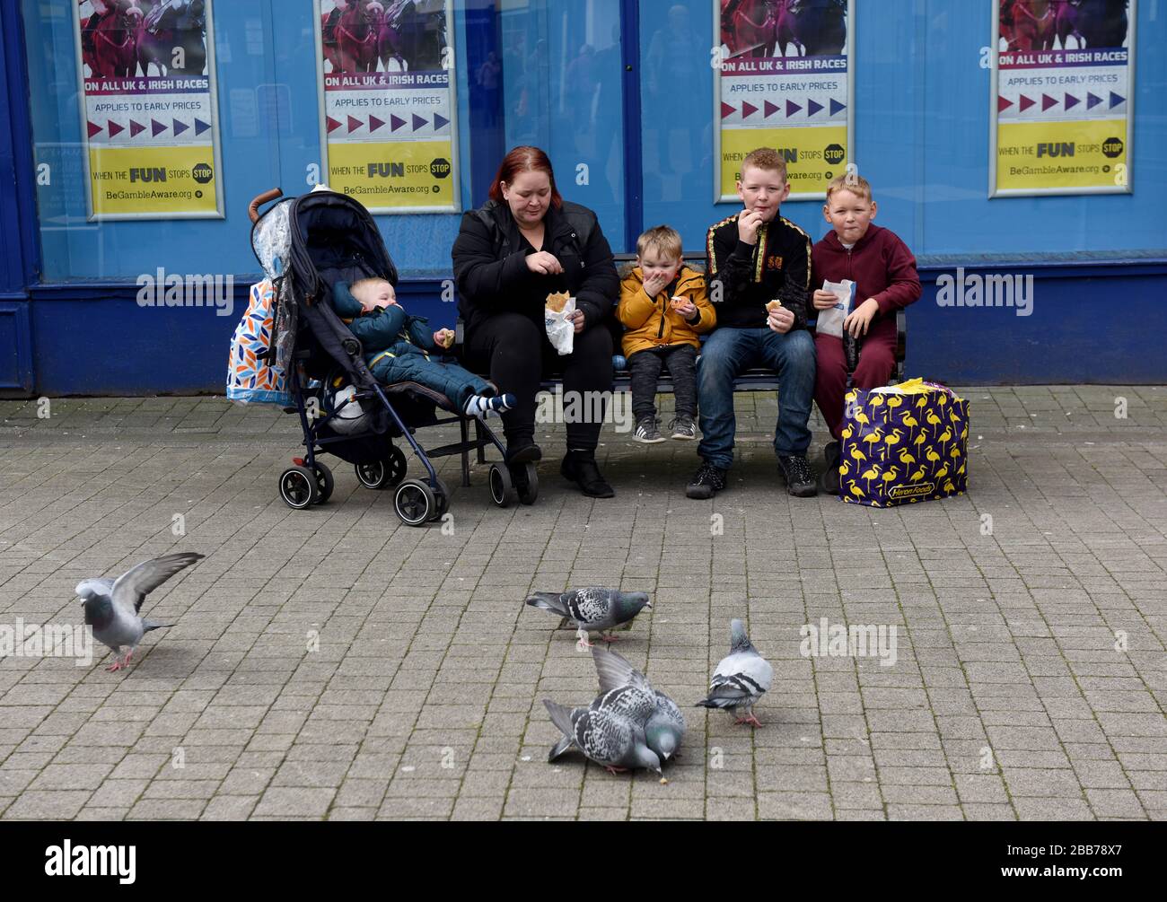 Mother and children eating take away food on public bench in Wellington town centre Britain Uk Stock Photo