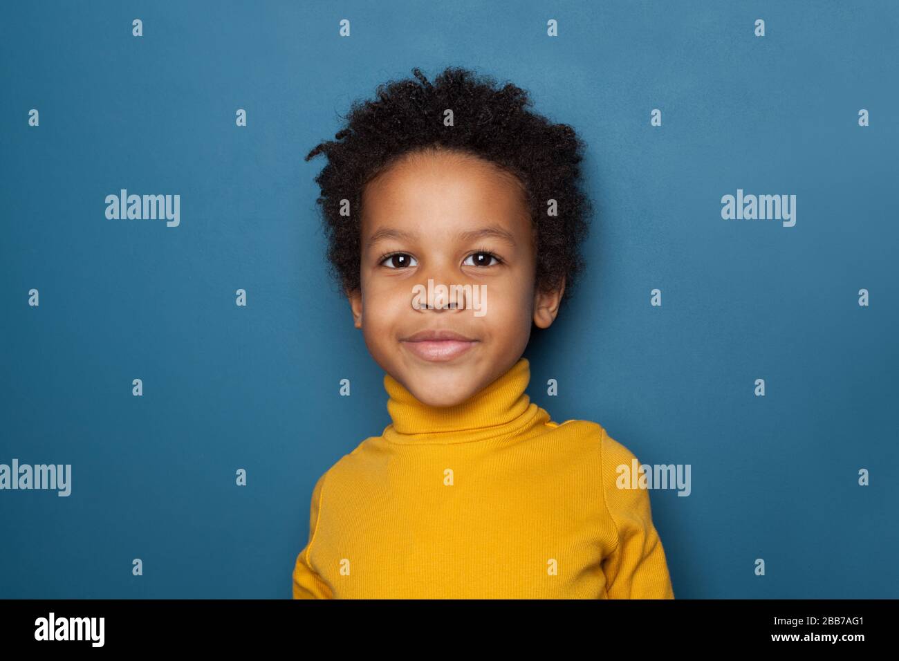 Curious black kid portrait. Little child boy smiling on blue background Stock Photo