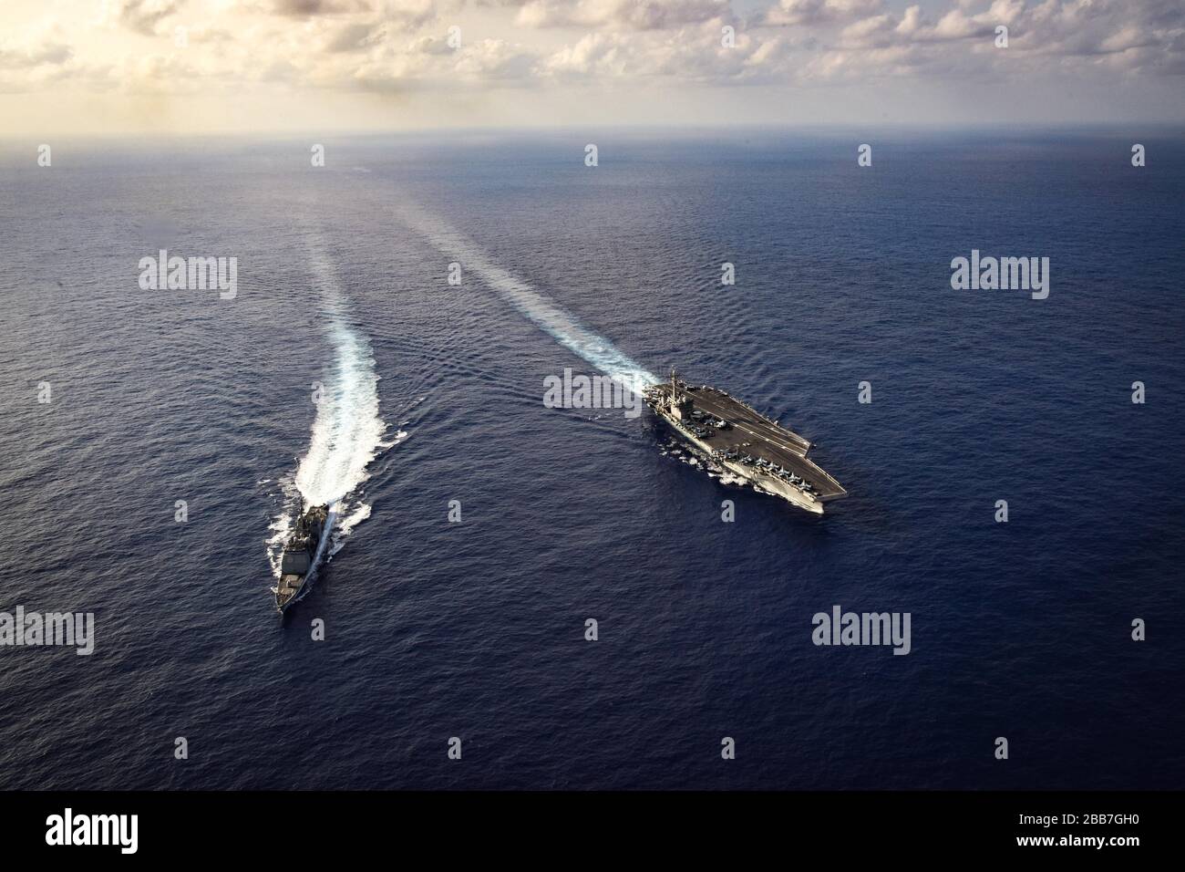 The U.S. Navy Nimitz-class aircraft carrier USS Theodore Roosevelt in formation with the Arleigh Burke-class guided-missile destroyer USS Bunker Hill as they perform a routine transit March 18, 2020 in the Philippine Sea. Stock Photo