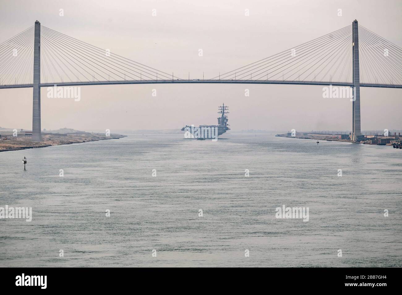 The U.S. Navy Nimitz-class aircraft carrier USS Dwight D. Eisenhower crosses under the Mubarak Peace Bridge as it transits the Suez Canal March 9, 2020 in El Qantara, Egypt. Stock Photo