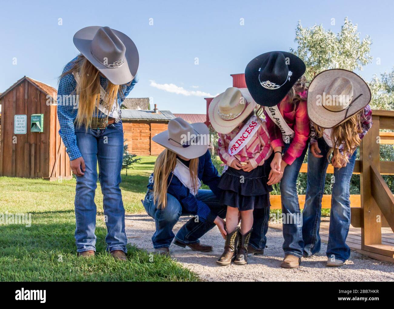 Newly crowned Pioneer Days Rodeo royalty teach the Princess how to stand in the royal pose of one leg slightly in front of the other. Stock Photo