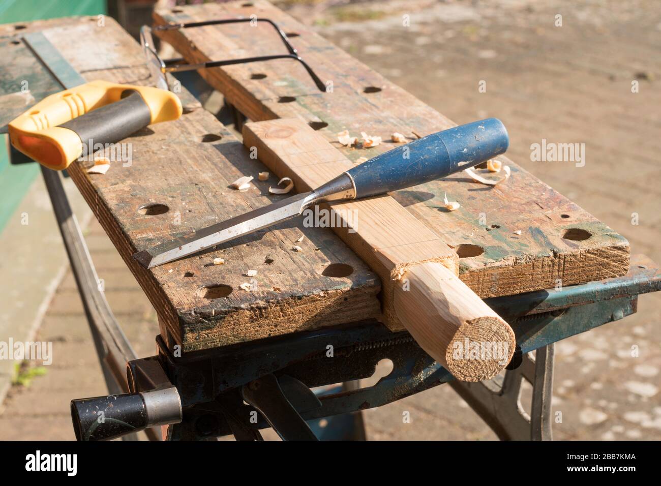 DIY a wooden workpiece held in a Workmate vice with a wood chisel, saw and spectacles in the background Stock Photo