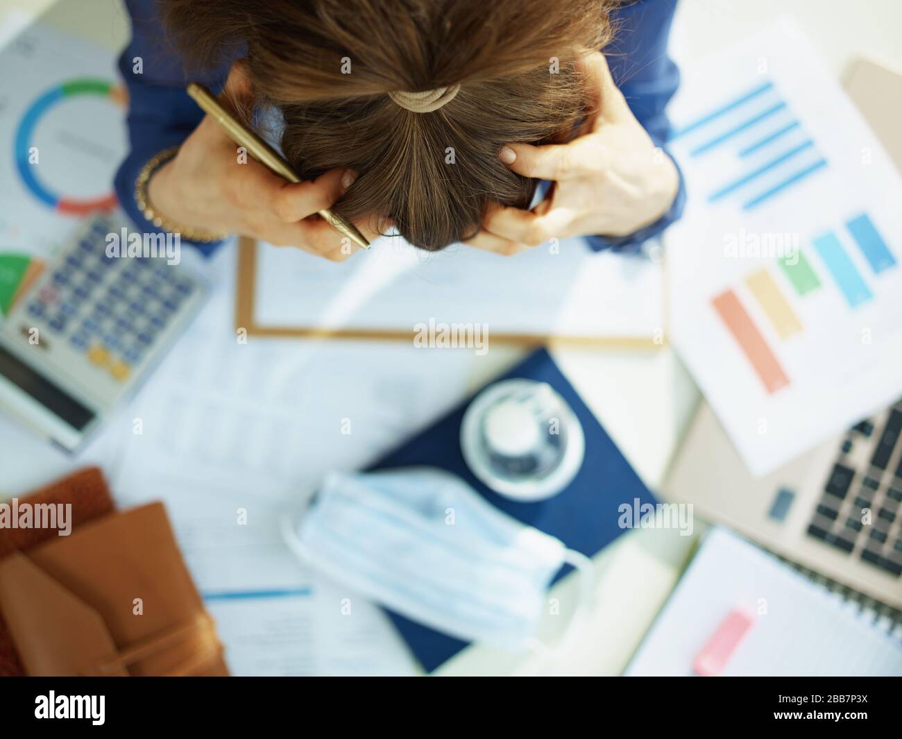 Upper view of stressed middle age business woman at the table. Stock Photo