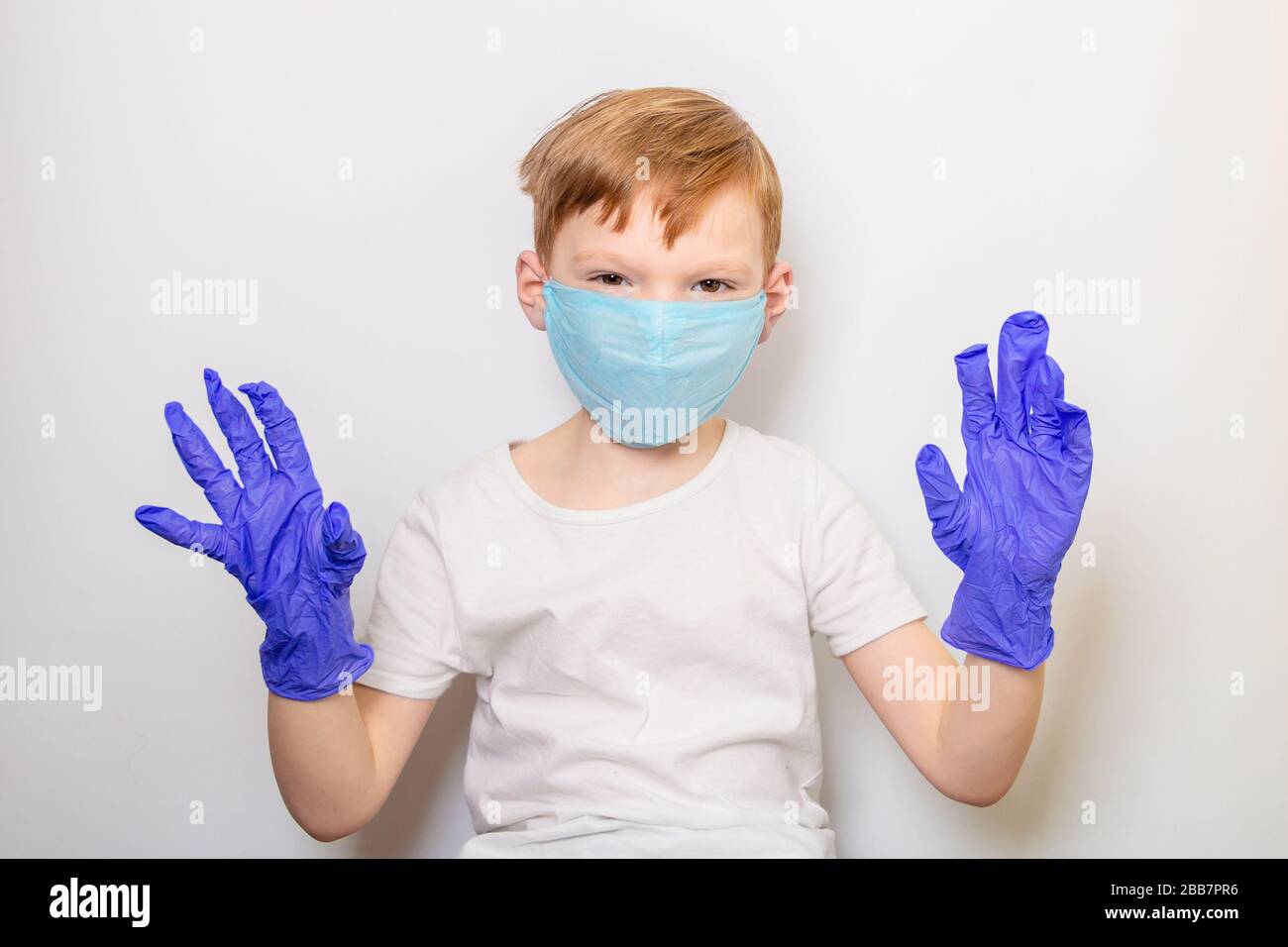 Seven year old boy in medical mask and latex gloves on a white background. Victory over Caronavirus Concept Stock Photo