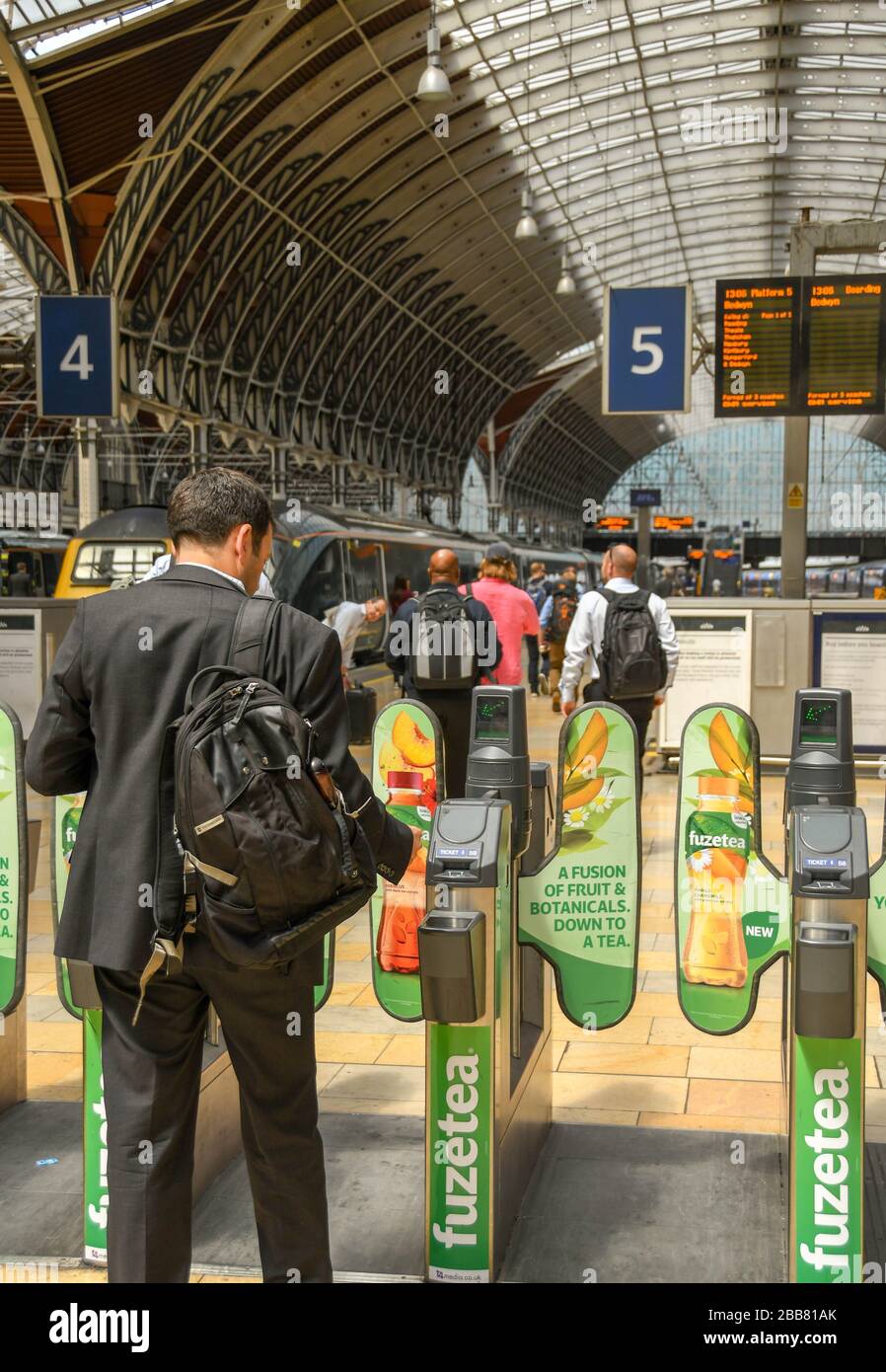 LONDON, ENGLAND - JULY 2018: Rail traveller passing through an automatic ticket barrier on the concourse at London Paddington railway station Stock Photo