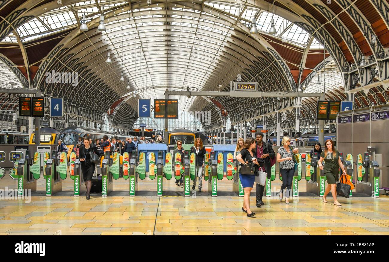 LONDON, ENGLAND - JULY 2018: Rail travellers leaving the platform at London Paddington Station through automatic ticket barriers. Stock Photo