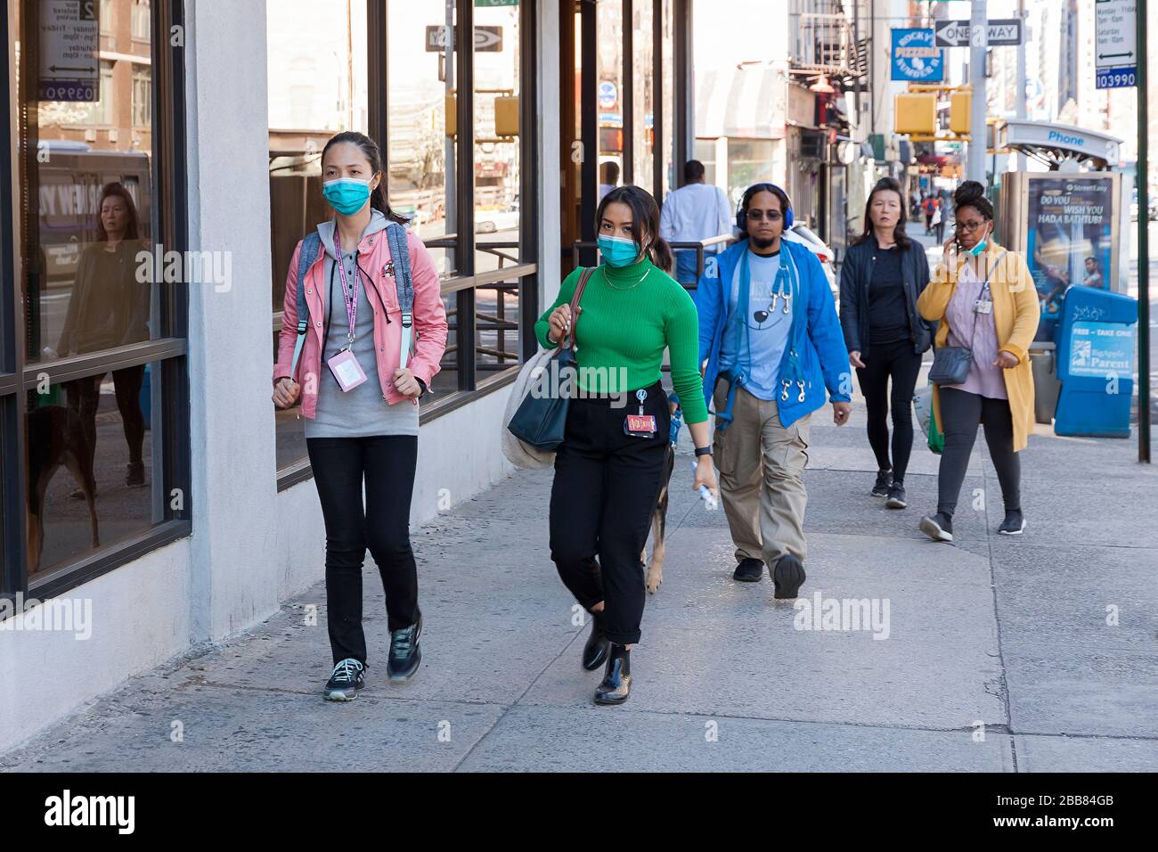 People wearing face masks while walking the sidewalks of New York City during the Covid-19 (coronavirus) epidemic. Stock Photo
