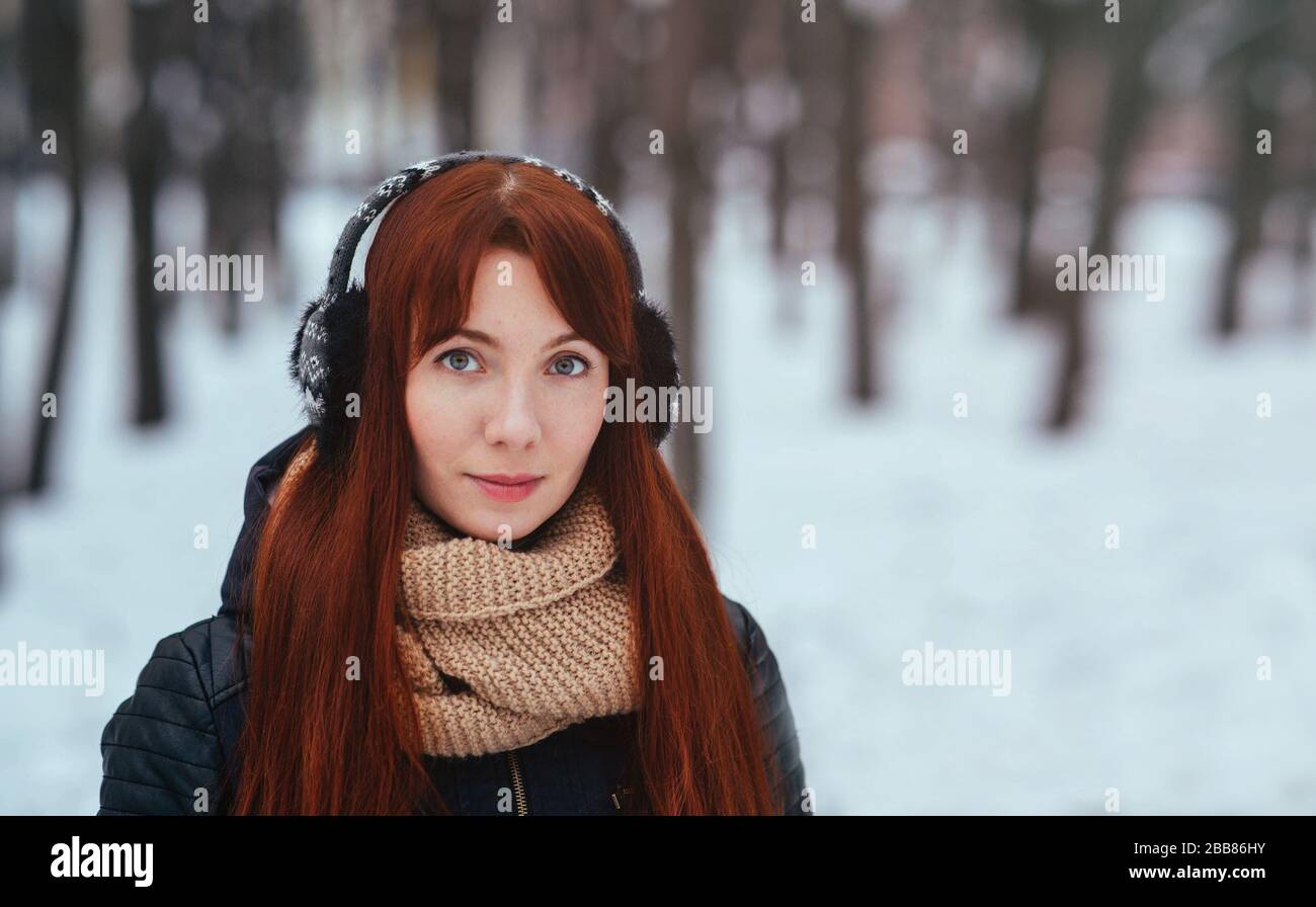 Winter. Woman with red hair wearing ear muffs looking at the camera Stock Photo