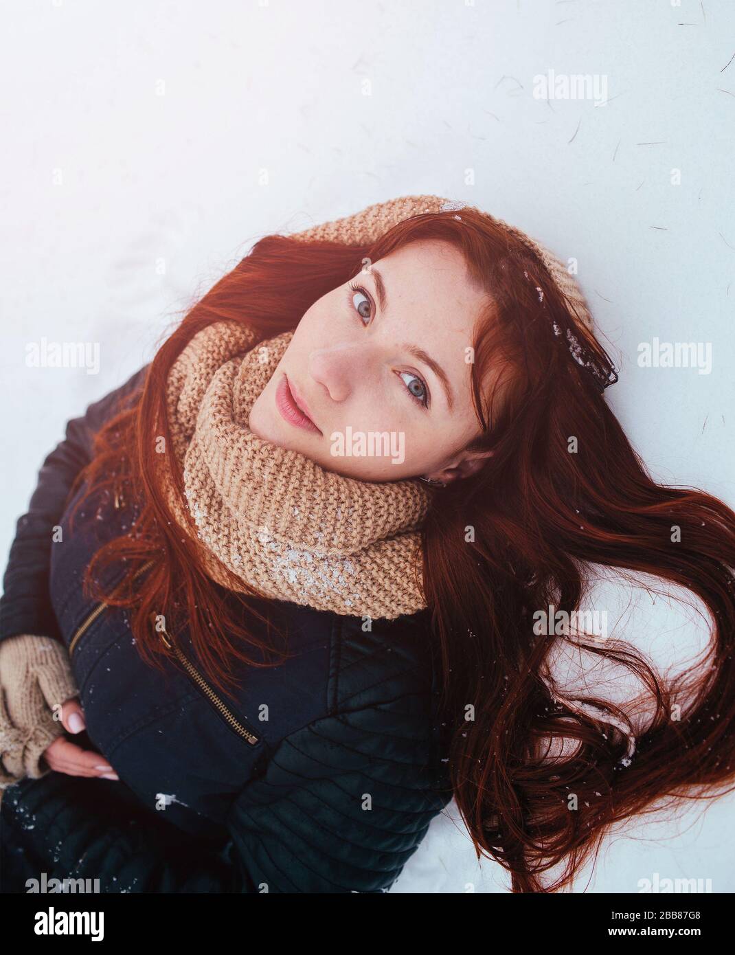 Winter. Woman with red hair wearing ear muffs looking at the camera. Stock Photo