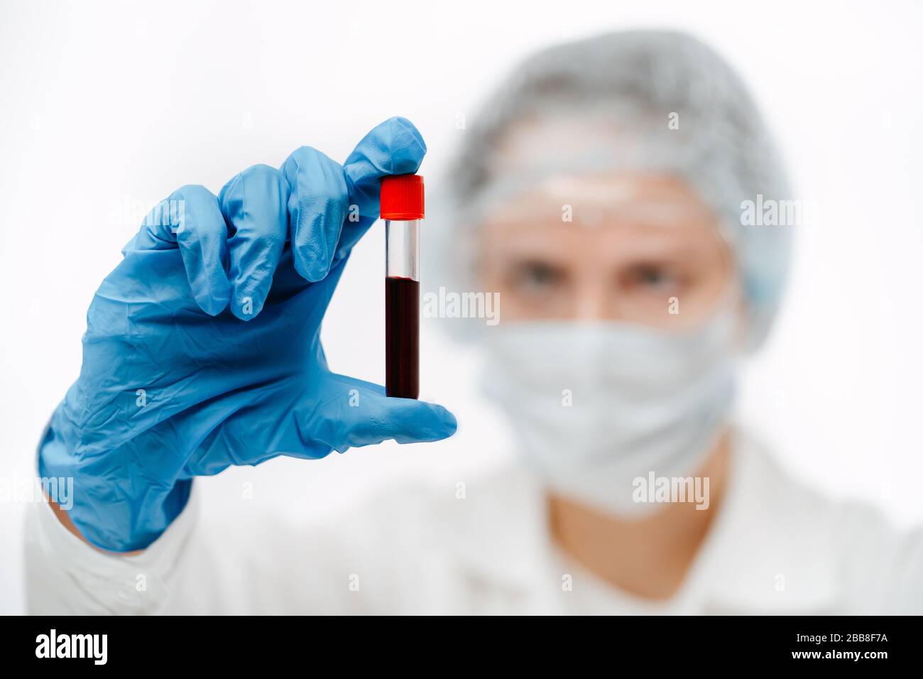 concentrated doctor in gloves holding tube of blood sample for coronavirus test Stock Photo