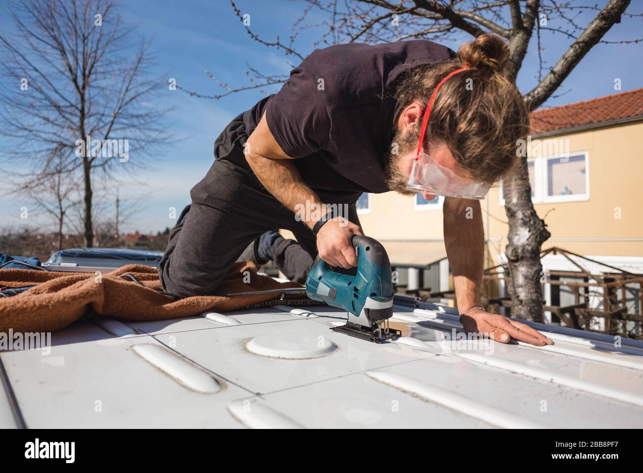 Man using a jigsaw to cut a hole into his van Stock Photo Alamy