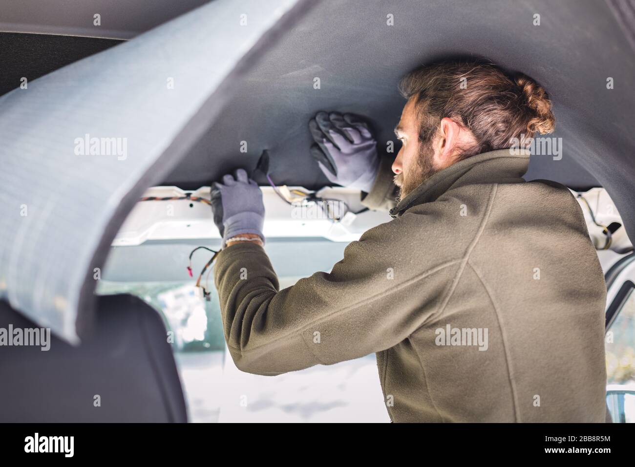 Man working on insulation inside his camper van Stock Photo