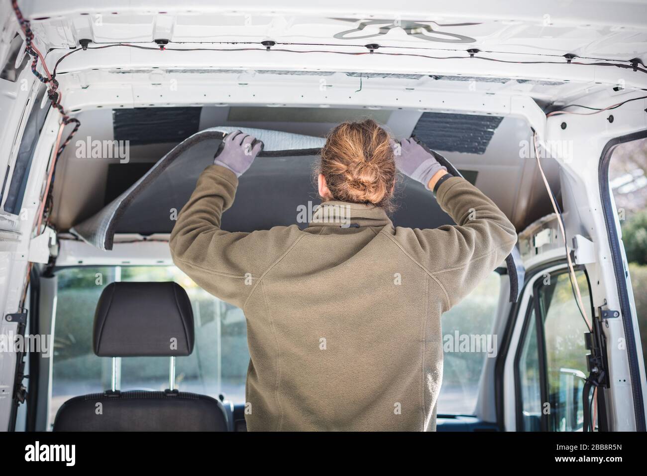 Man working on insulation inside his camper van Stock Photo