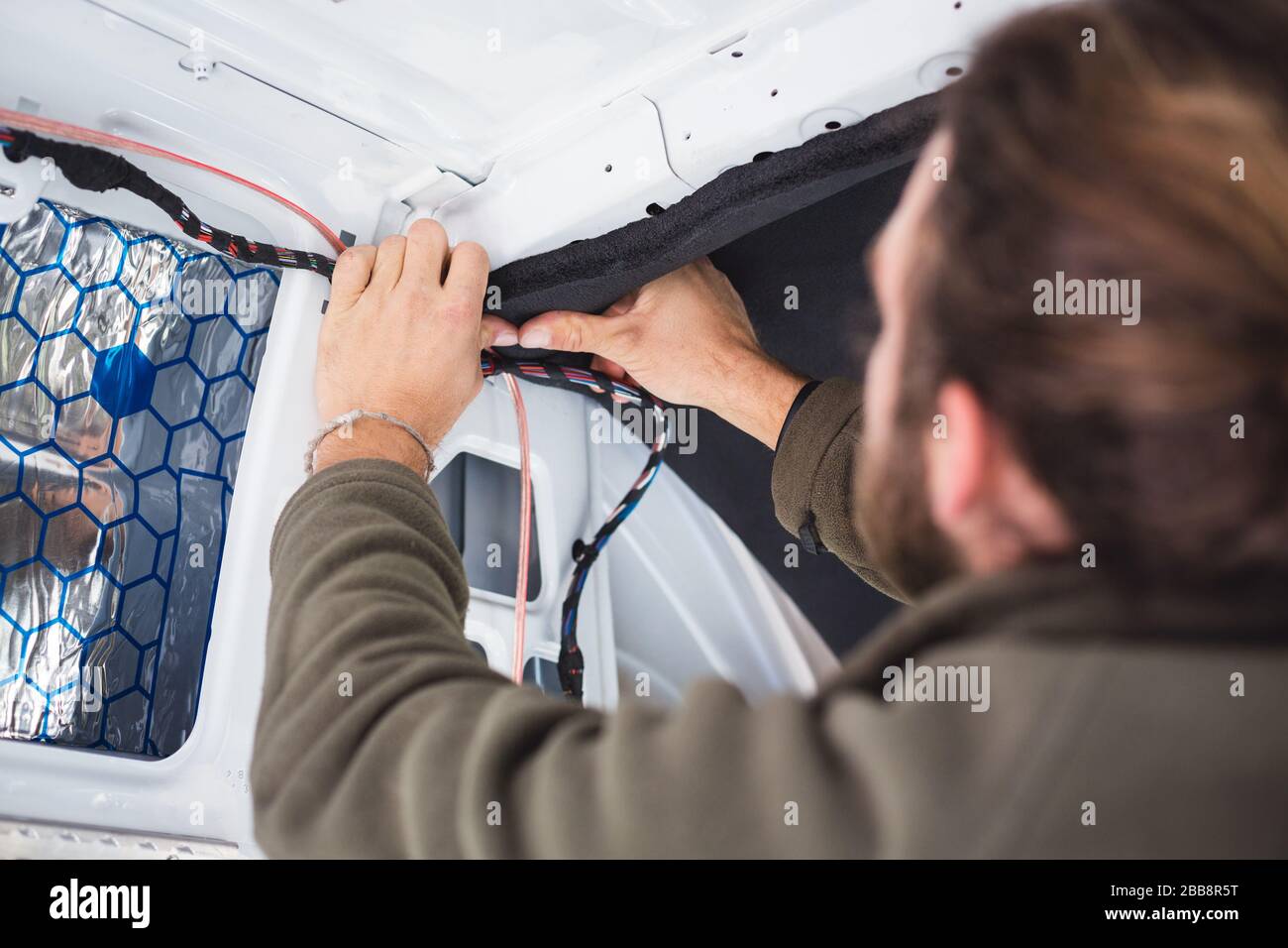 Man working on insulation inside his camper van Stock Photo