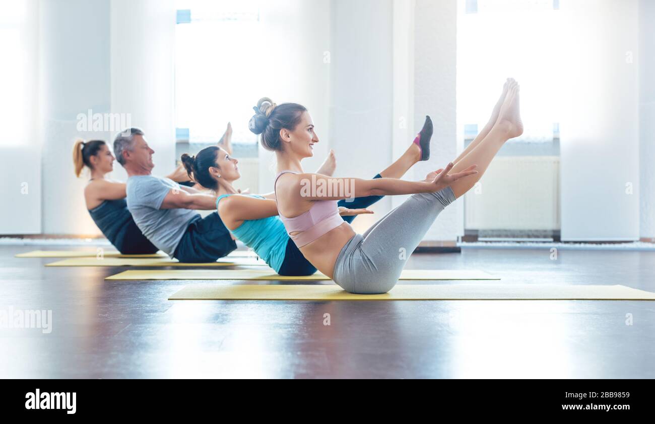 Women and men having a yoga class doing the boat pose Stock Photo