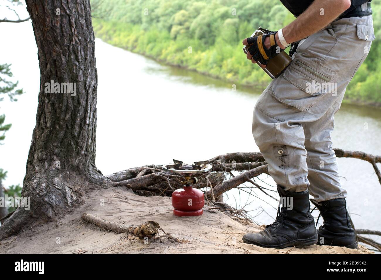 Traveler In Leather Boots Prepares For A Gas Burner Food Over Cliff Above The River Stock Photo Alamy