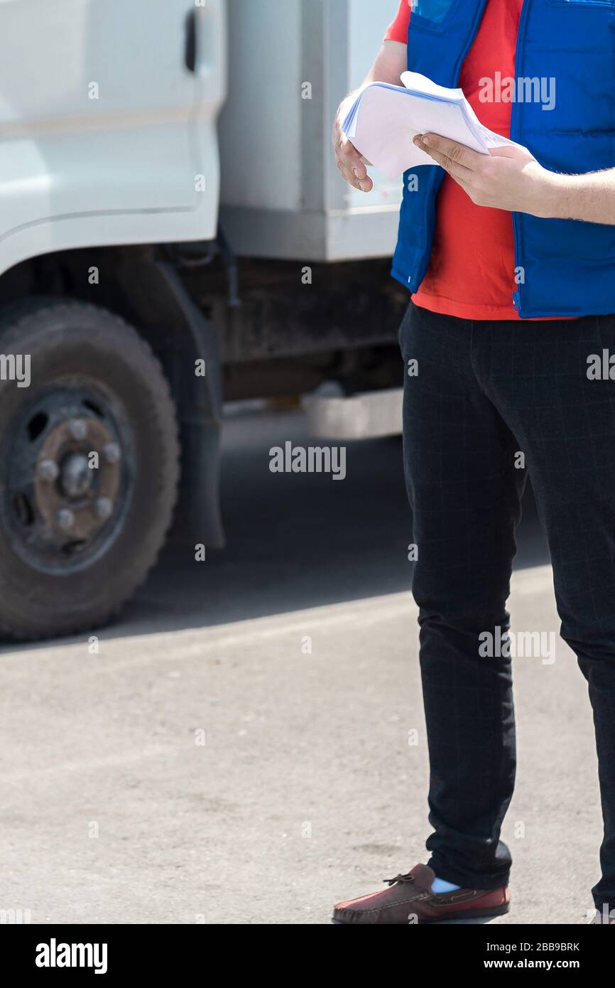 Driver Making Notes Courier driver in uniform making notes in document and delivery white ...