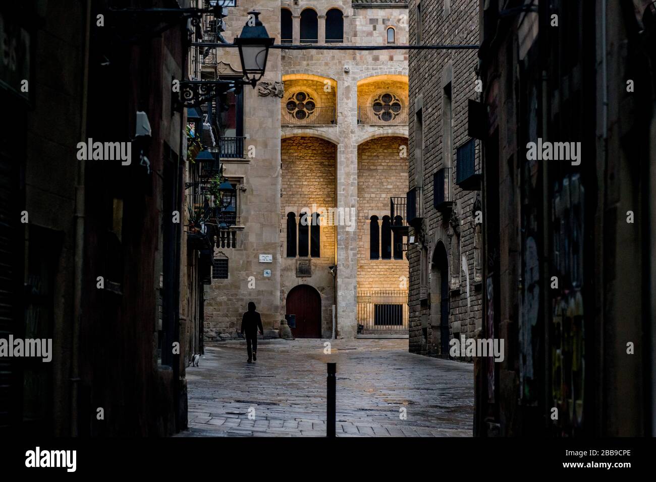 Barcelona, Catalonia, Spain. 30th March 2020. A man walks the empty streets of Barcelona's Gothic Quarter under the rain. Daily coronavirus deaths fall slightly with 812 Covid-19 victims in the last 24 hours in Spain, Spanish government has ordered new lockdown restrictions. Credit:Jordi Boixareu/Alamy Live News Stock Photo