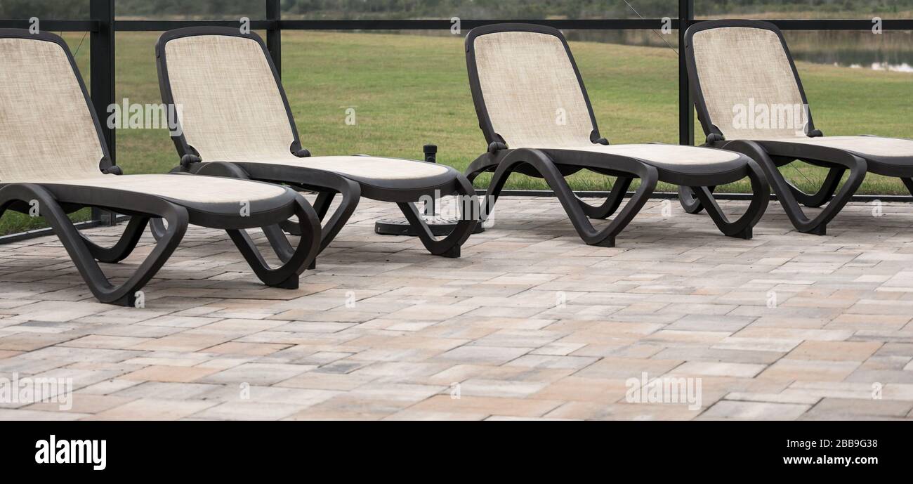 Four tan lawn chairs inside a screened pool area Stock Photo Alamy