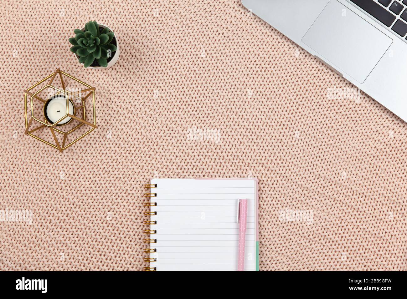 Work from home concept. Modern female working space, top view. Laptop, cactus, candle, notebook on knitted blanket, copy space, flat lay. Desktop of f Stock Photo