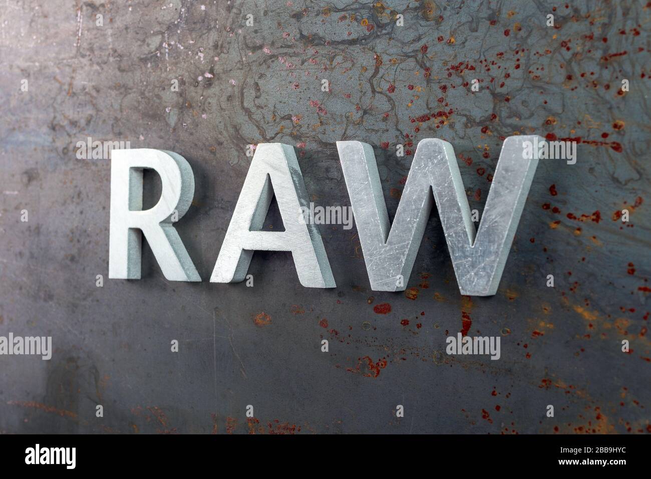 the word raw laid with silver metal letters on hot rolled steel sheet surface - close-up with selective focus and skewed perspective Stock Photo