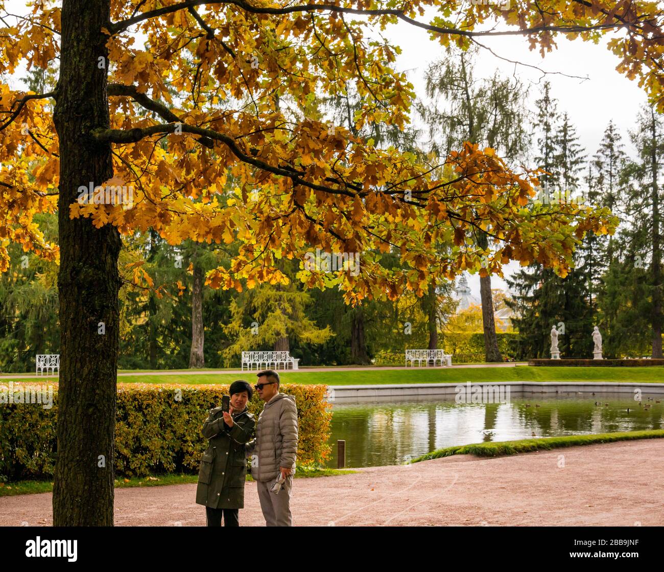 Asian tourist couple taking selfie by lake, Catherine Park, Tsars Village, Tsarskoe Selo, Pushkin, Russian Federation Stock Photo