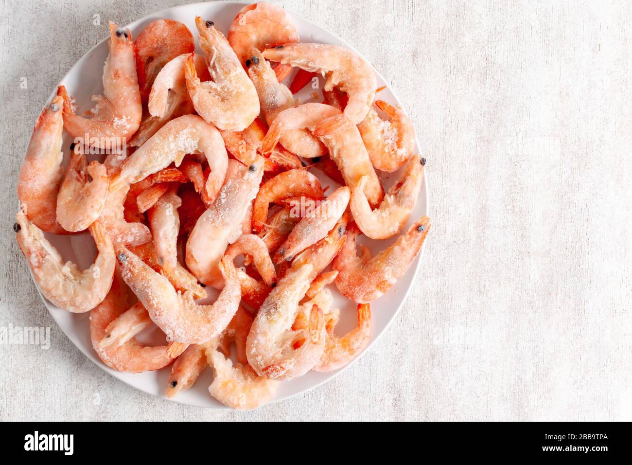 Frozen king prawns on a white plate on a light background Stock Photo