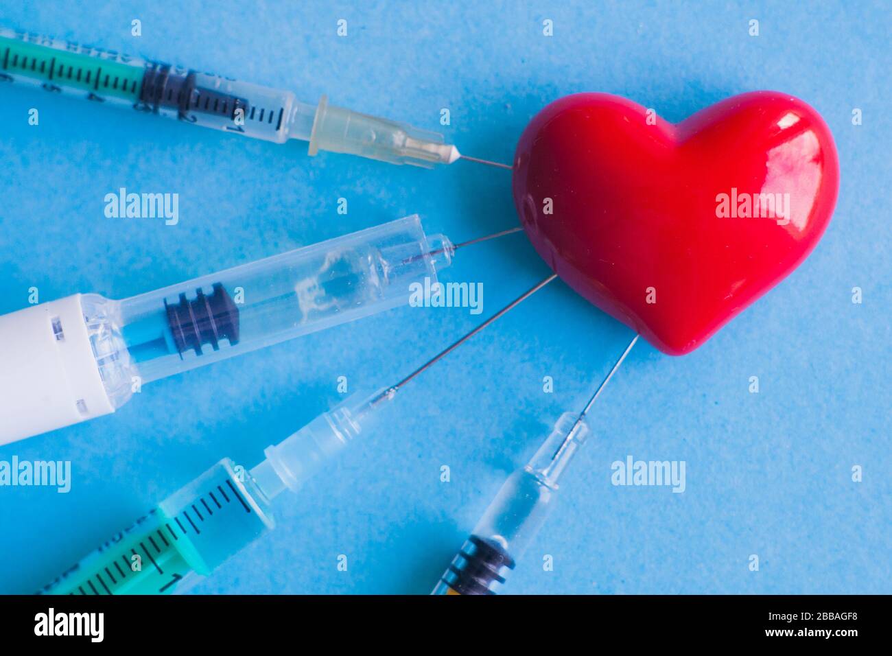 volumetric heart with syringes on a pink background. The concept of ...