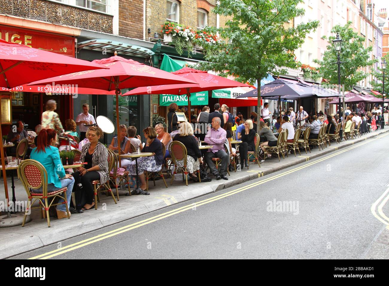 PEOPLE DINING OUTSIDE ON THE DESIGNATED AREA FOR DRINKING, DINING AND SOCIALISING. RESTAURANT TRADE. RESTAURANT BUSINESS. TOURISM IN LONDON, UK. AUTHENTIC IMAGERY. STREET PHOTOGRAPHY. PEOPLE ENJOYING THEMSELVES. SOCIAL LIFE.  HUMAN CONDITION. Stock Photo