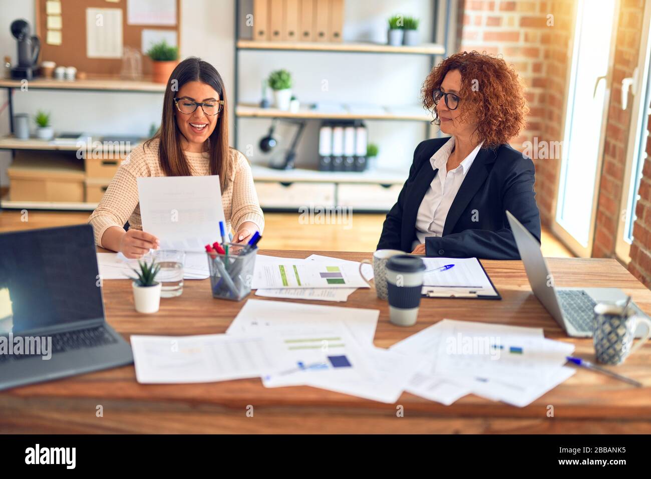 Two beautiful businesswomen smiling happy and confident. Sitting with ...