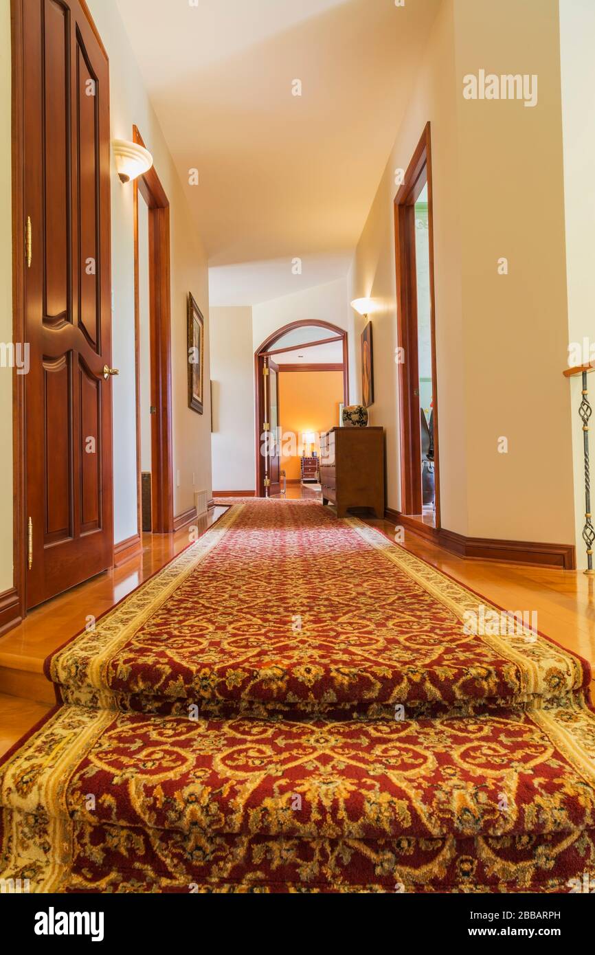 Hallway with burgundy and cream coloured rug runner leading to bedrooms on upstiars floor inside a luxurious residential home, Quebec, Canada. This image is property released. CUPR0341 Stock Photo