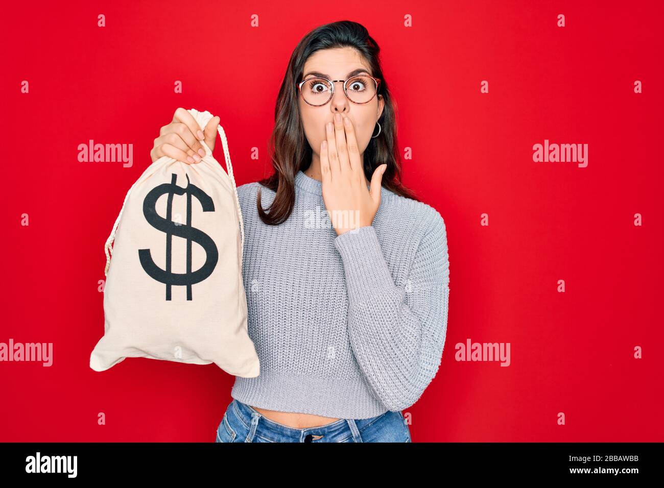 Young beautiful girl holding money bag with dollar symbol for