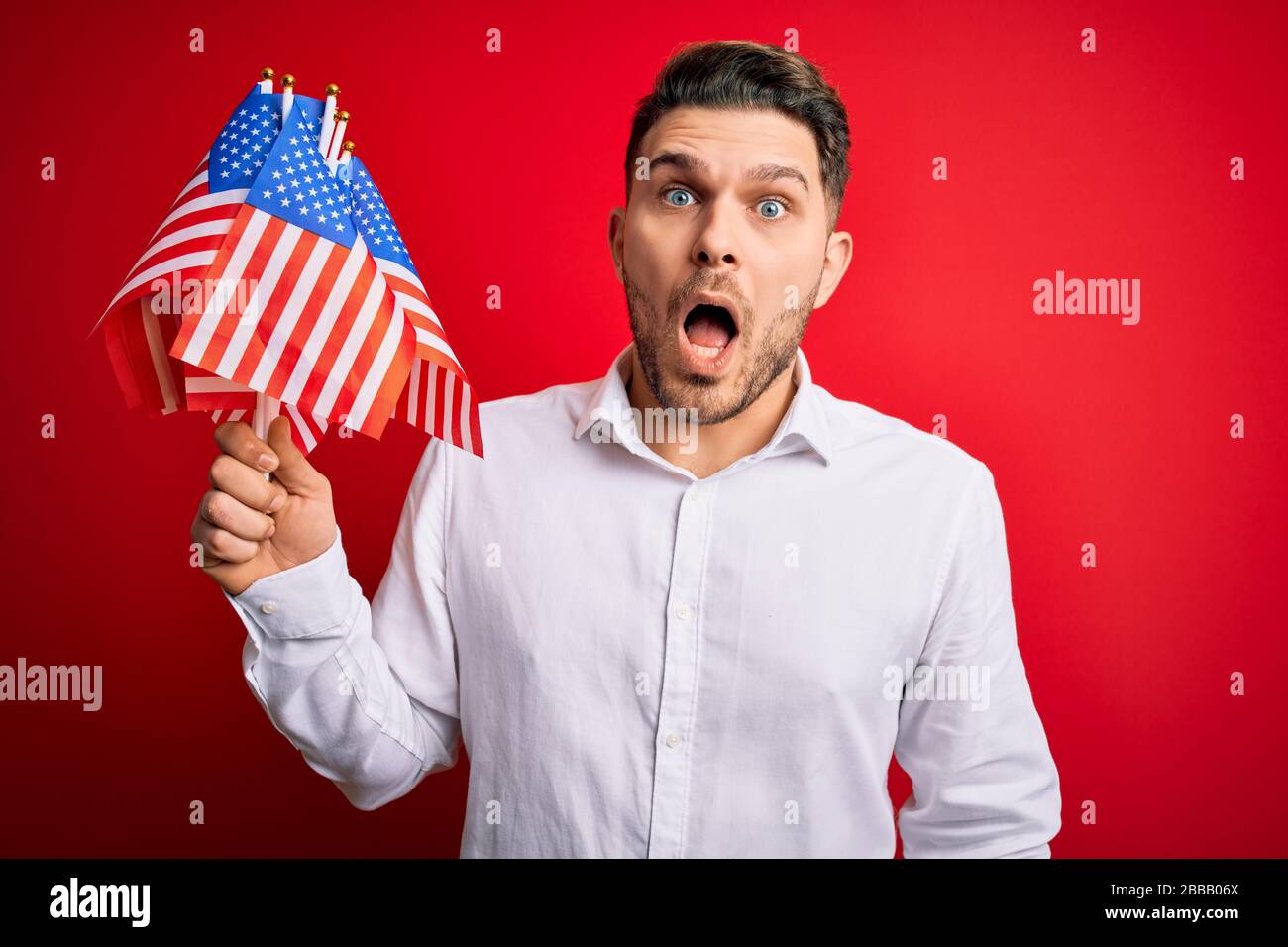 Young man with blue eyes holding flag of united states of america over ...