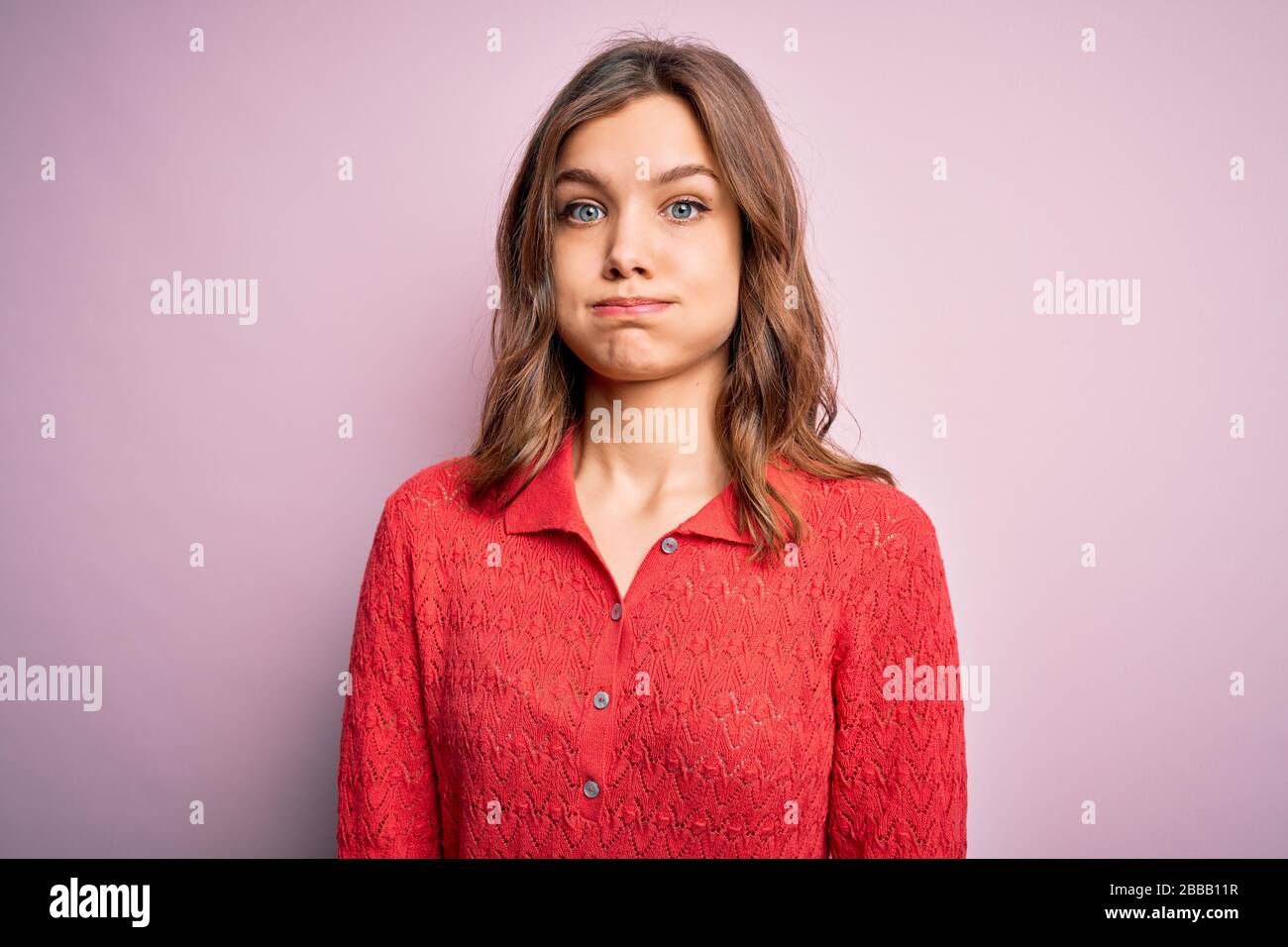 Young beautiful blonde casual girl over pink isolated background puffing cheeks with funny face. Mouth inflated with air, crazy expression. Stock Photo