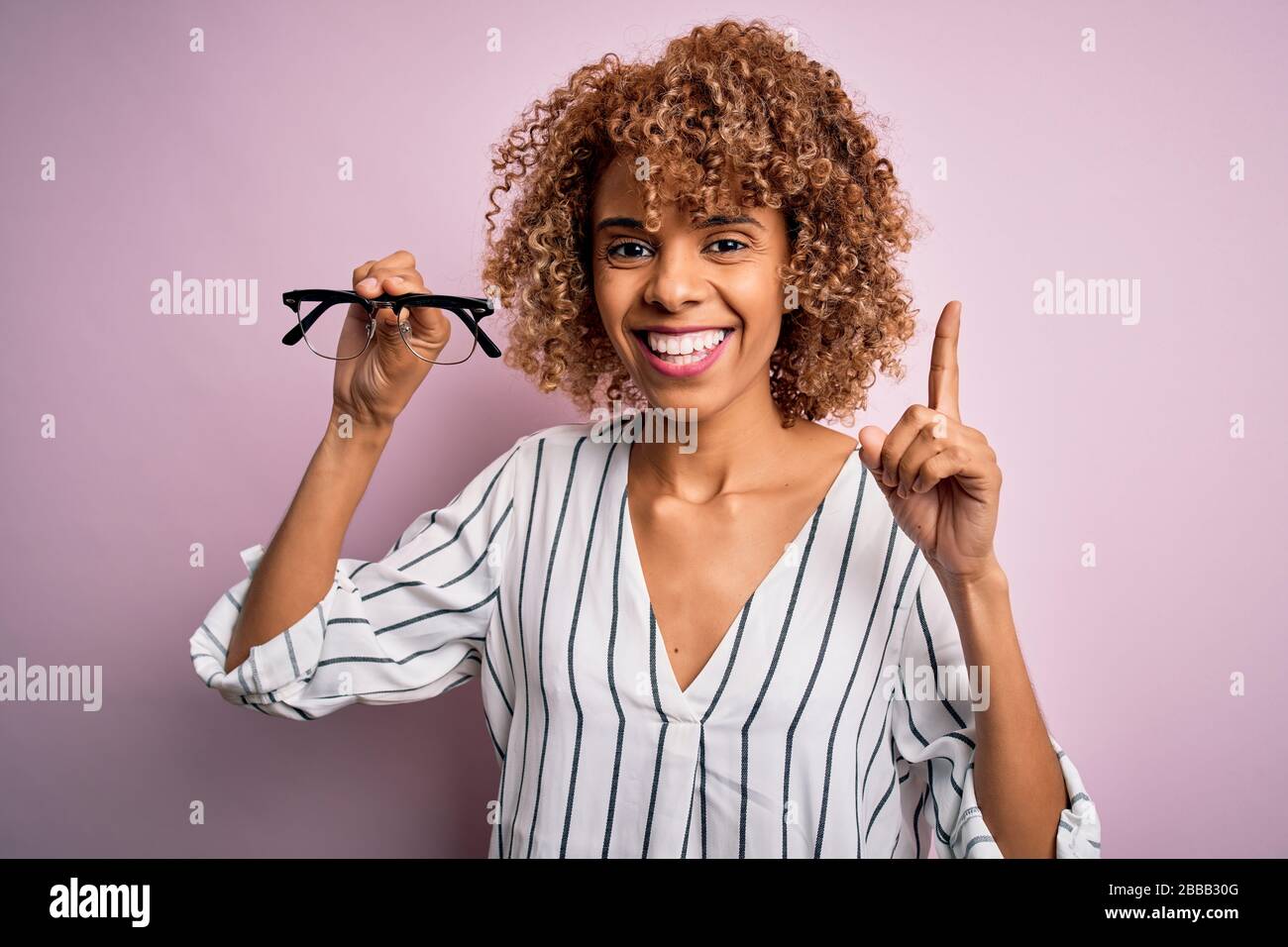 African american optical woman with curly hair holding glasses over ...
