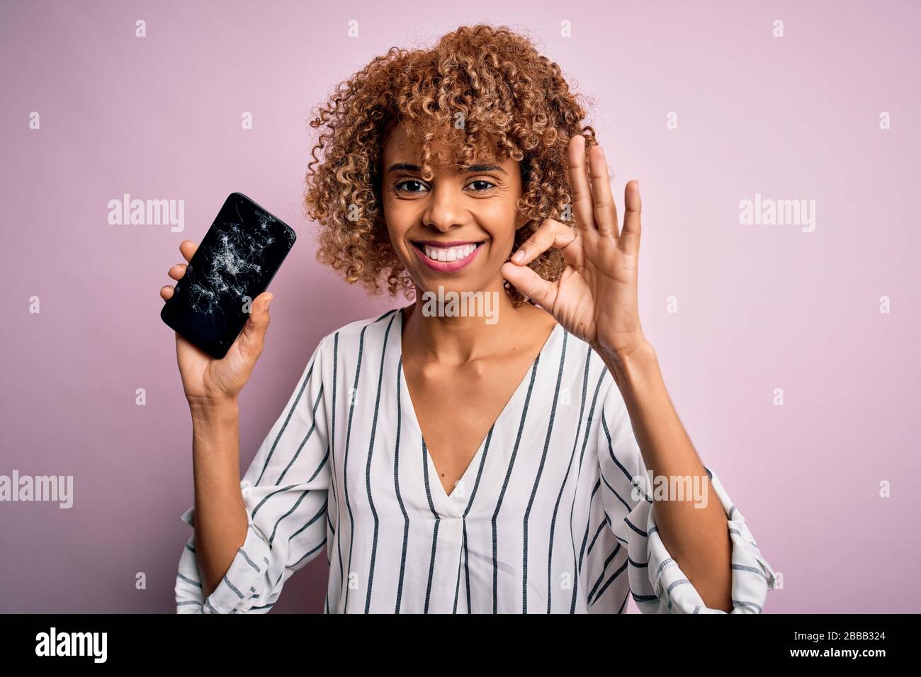 Young african american curly woman holding broken smartphone showing ...