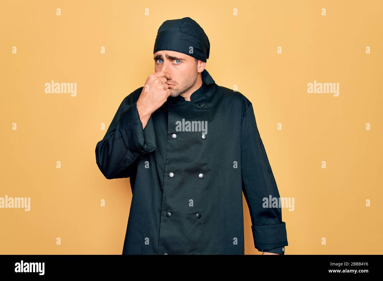Young handsome cooker man with blue eyes wearing uniform and hat over ...