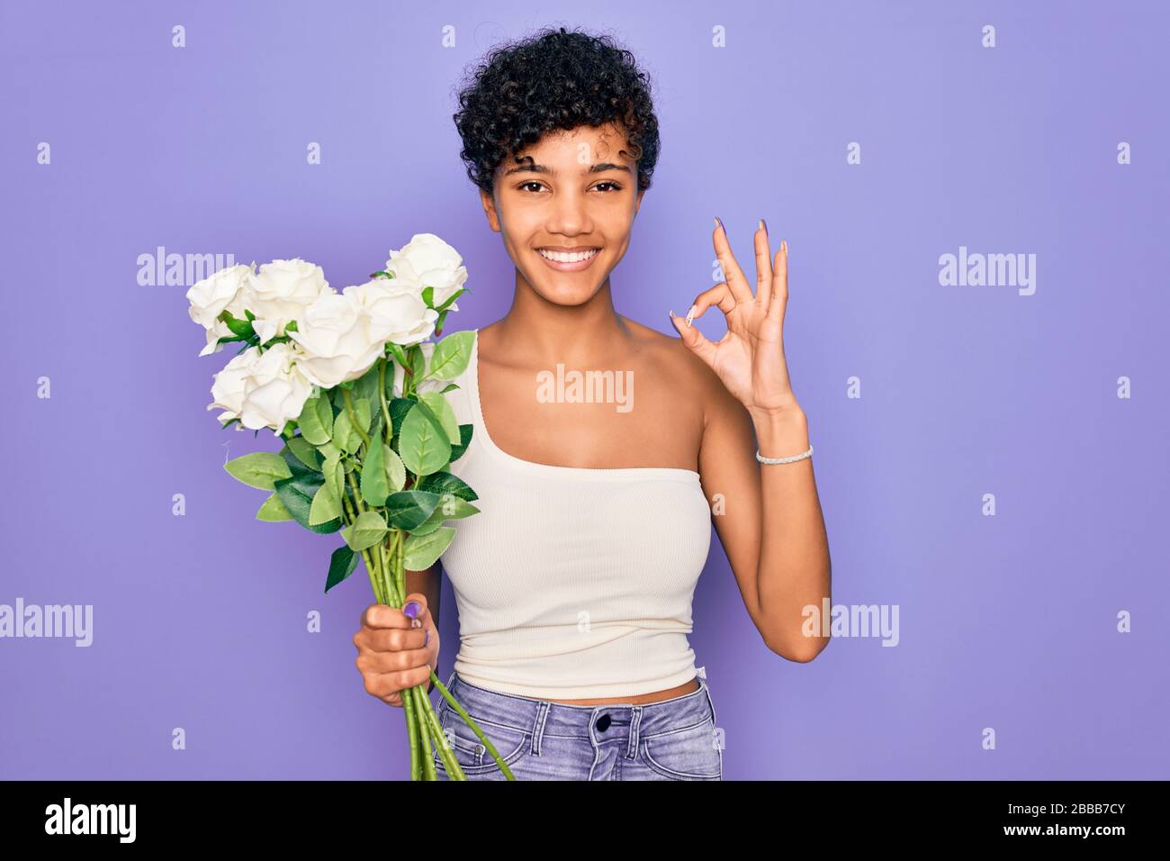 Beautiful african american afro woman holding bouquet of white flowers ...