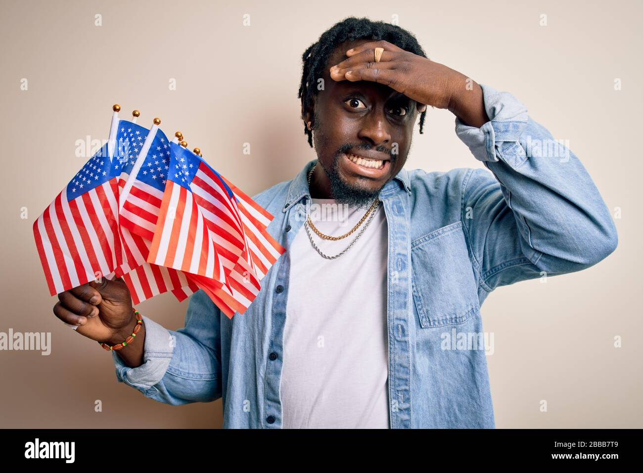 Young african american patriotic man holding united states flags over ...