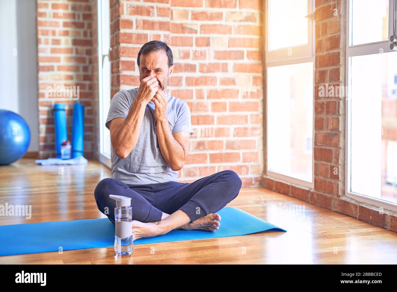 Middle age handsome sportman sitting on mat doing stretching yoga