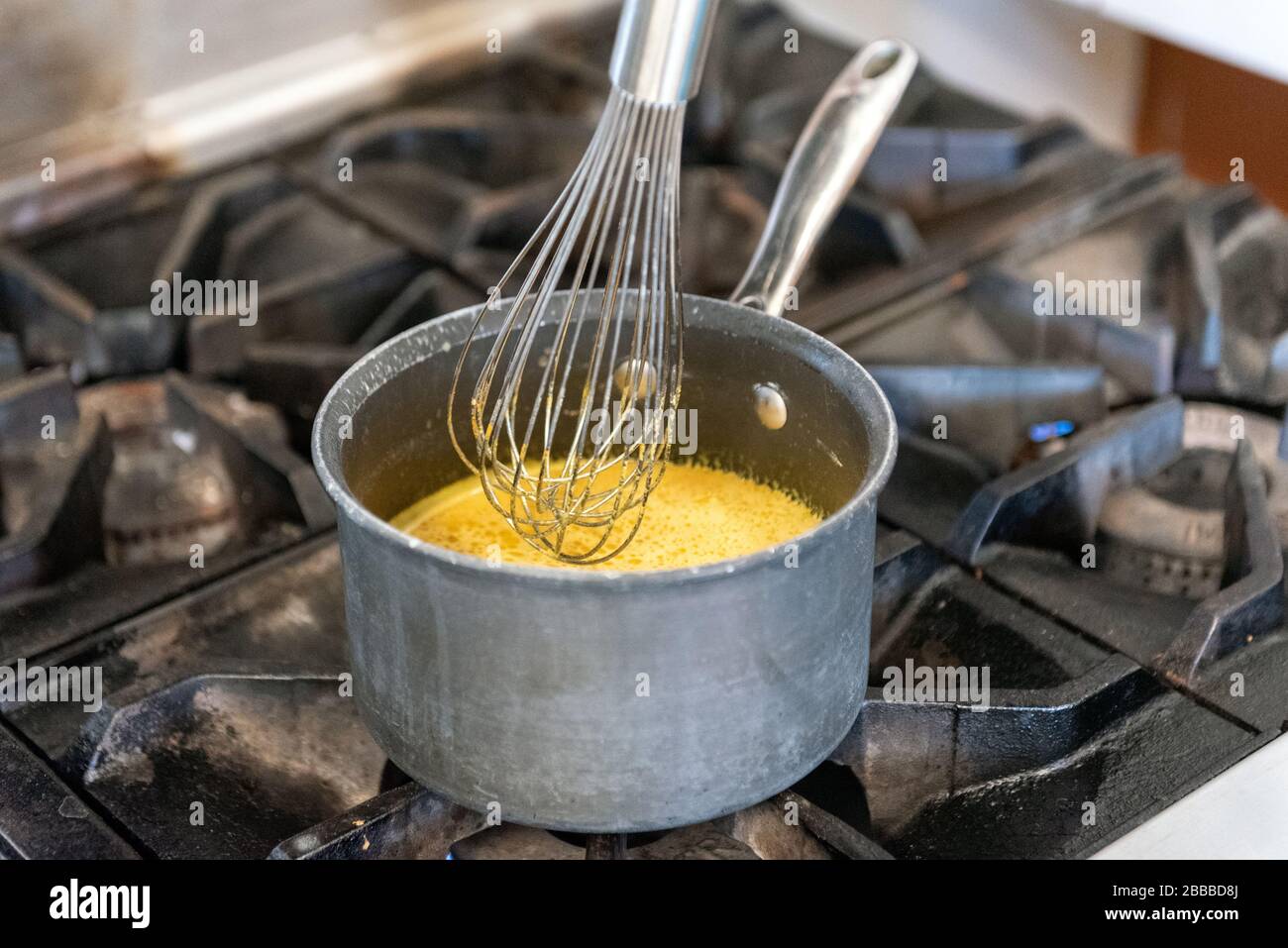 Home made healing tea is heating on the stove top while whisking the
