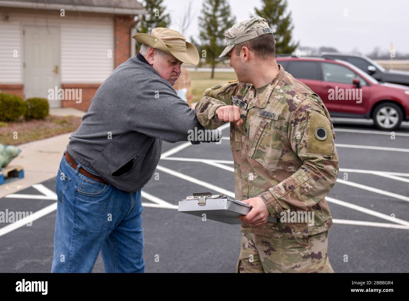 U.S. Army Sgt. Jeffrey Habeck, a Soldier assigned to the Ohio National Guard’s 1-148th Infantry Regiment – 37th Infantry Brigade Combat Team, bumps elbows with a volunteer at Waterville Community Church after delivering food items from the Toledo Northwestern Ohio Food Bank in Toledo, Ohio, March 24, 2020. Nearly 400 Ohio National Guard members were activated to provide humanitarian missions in support of COVI-19 relief efforts, continuing the Ohio National Guard’s long history of supporting humanitarian efforts throughout Ohio and the nation.  (U.S. Air National Guard photo by Senior Airman K Stock Photo