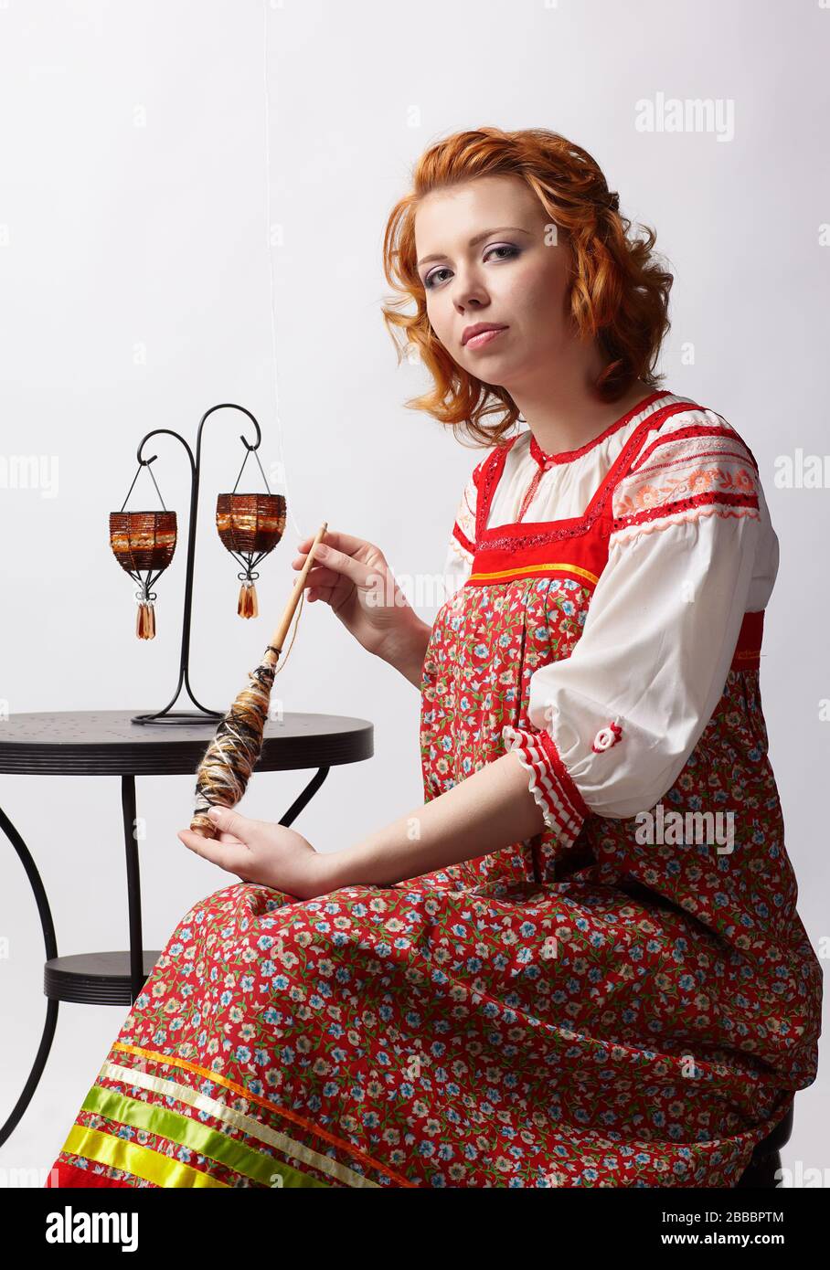 portrait of beautiful slavonic redhead girl in traditional russian folk dress with distaff Stock Photo