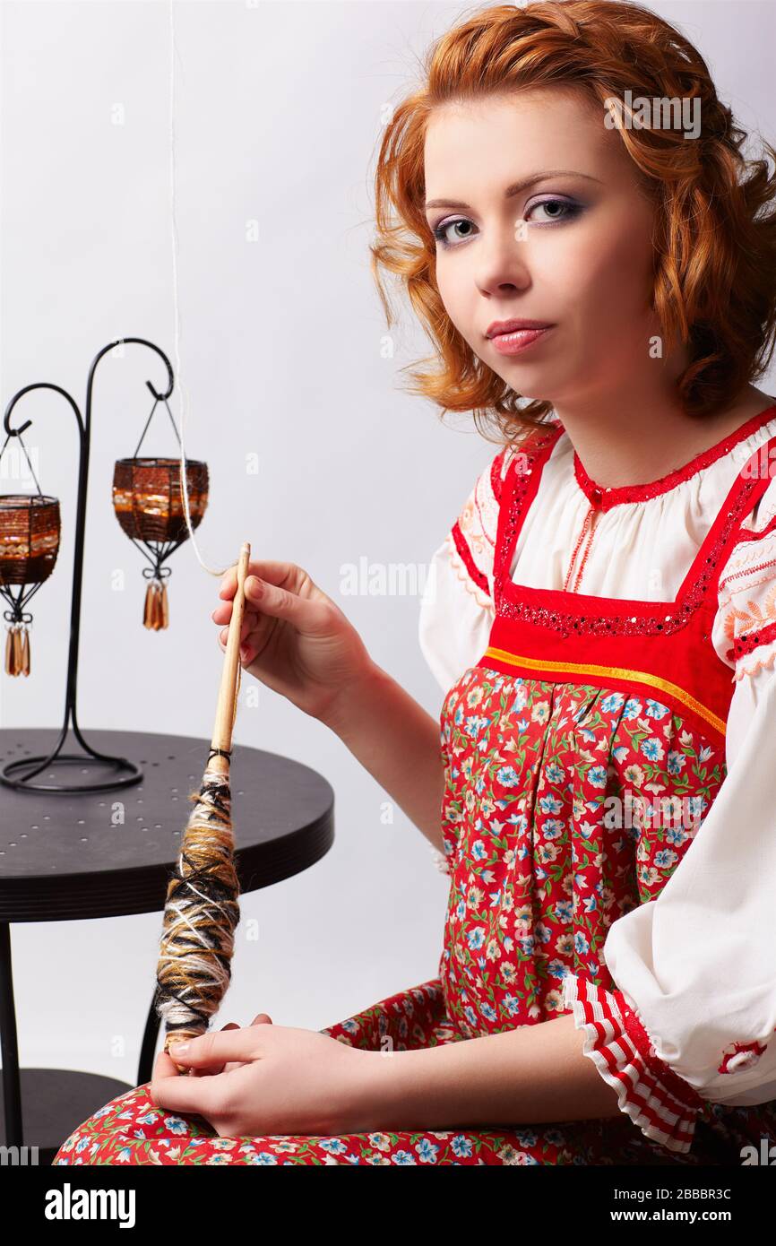portrait of beautiful slavonic redhead girl in traditional russian folk dress with distaff Stock Photo