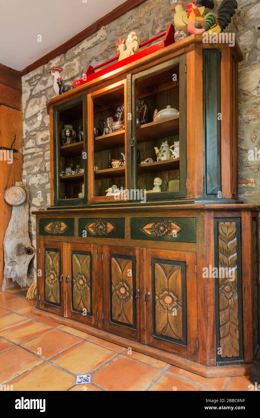 Hand-carved wooden buffet against an old fieldstone wall in the dining room with terracotta ceramic tile flooring inside an old circa 1830 Quebecois style country home, Quebec, Canada. This image is property released. CUPR0357 Stock Photo