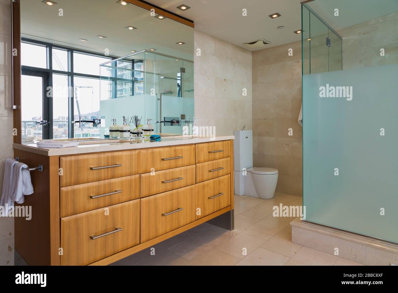 Exotic wood vanity and glass shower stall in en suite with marble tile floor inside a modern luxurious multistory penthouse condominium unit, Old Montreal, Quebec, Canada. This image is property released for publication in calendars and editorial use. EUPR0359 Stock Photo