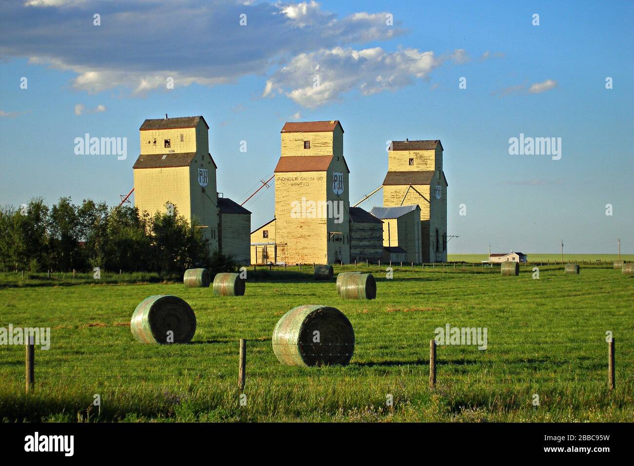 Alberta, Mossleigh, grain elevators and hay bales Stock Photo