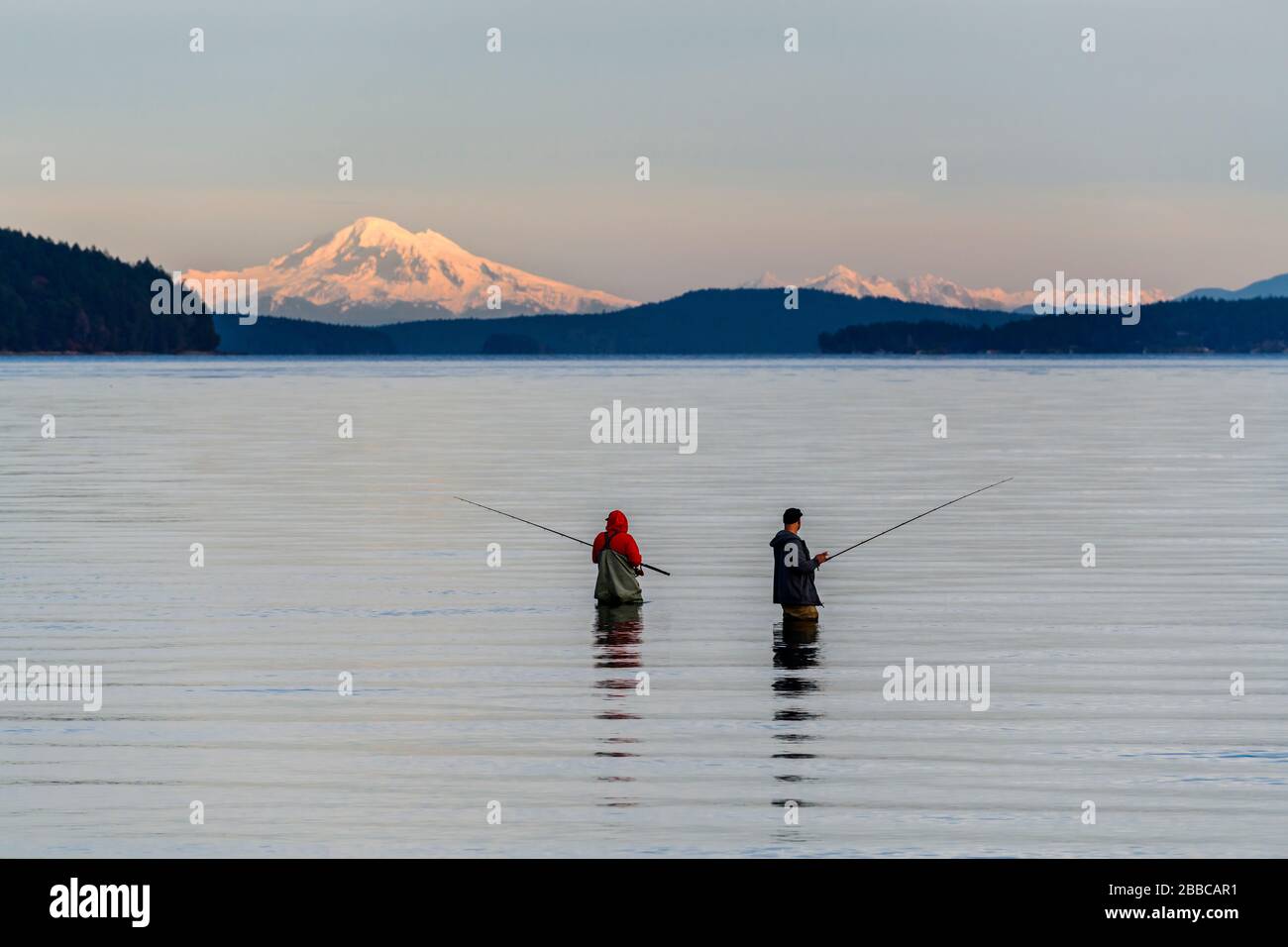 Two men ocean fishing at Cherry Point Beach near Cowichan Bay, British Columbia. Mt. Baker in Washington State is in the background. Stock Photo
